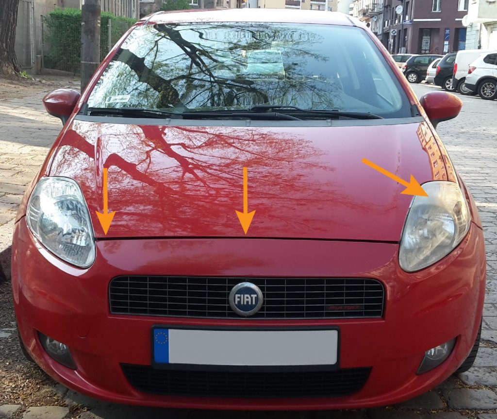 Uneven panel gap between the bonnet and the bumper, as well as a yellowed headlight, highlighted with arrows.
