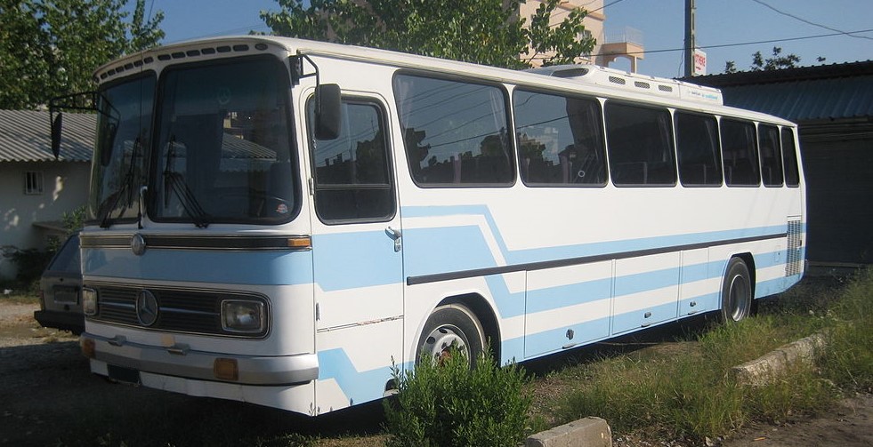 White Mercedes-Benz O 302 bus with blue stripes.