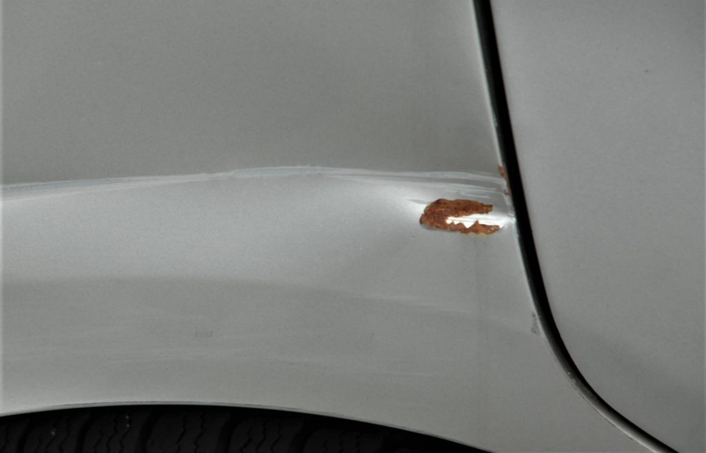Deep paint scratch on a used car that started corroding.