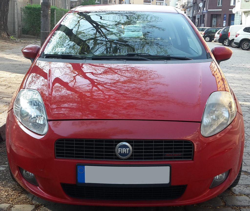 Front view of a Fiat car. Uneven panel gap above the grille and a yellowed right headlight visible.