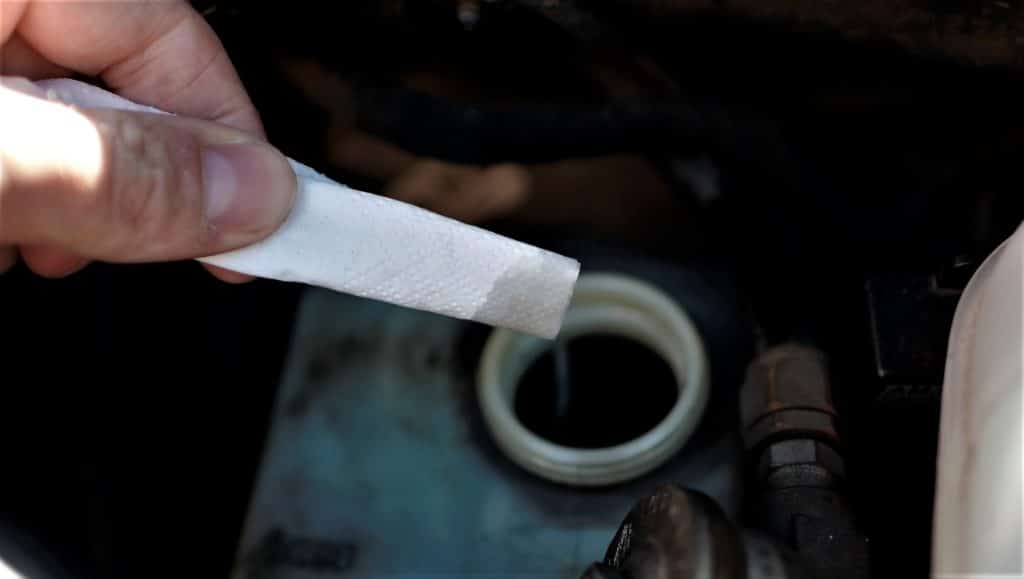 Brake fluid reservoir in a used car. The brake fluid appears dark but looks clear on a tissue.