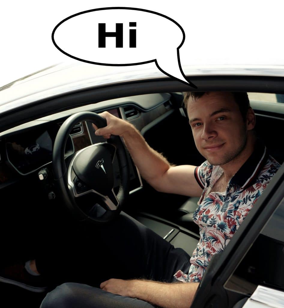 A handsome man in a floral shirt sitting inside a Tesla Model S.