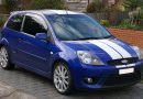 Used, blue Ford Fiesta ST (Mk5) with white racing stripes and OEM alloy wheels.